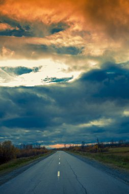 Kırık bir bölen şeridi ile bir asfalt yol boyunca dramatik gökyüzü