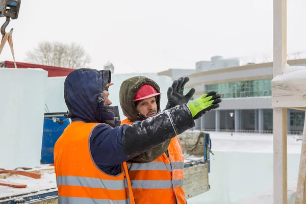 Workers build an ice town from ice blocks for the Christmas holidays