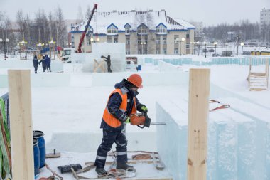 İşçi koruyucu bir kask içinde tesisatçısı ve yansıtıcı yelek bir buz levha testere ile kesme