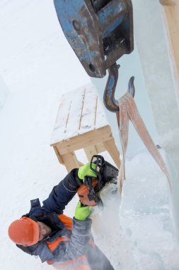İşçi koruyucu bir kask içinde tesisatçısı ve yansıtıcı yelek bir buz levha testere ile kesme