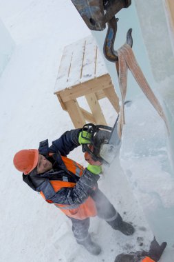 İşçi koruyucu bir kask içinde tesisatçısı ve yansıtıcı yelek bir buz levha testere ile kesme