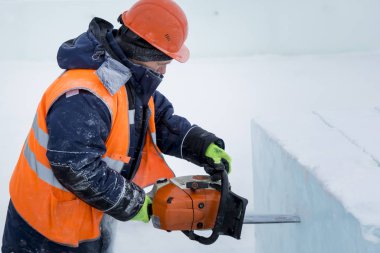 İşçi koruyucu bir kask içinde tesisatçısı ve yansıtıcı yelek bir buz levha testere ile kesme