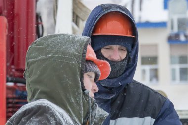 Bir konuşma için buz şehrin inşaat sahasında işçiler