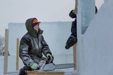 Ellerinde testere ile koruyucu bir kask içinde çalışma yükleyici ile asistan buz yapıları tesisatını-mektedir içinde nişanlı