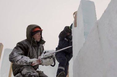 Ellerinde testere ile koruyucu bir kask içinde çalışma yükleyici ile asistan buz yapıları tesisatını-mektedir içinde nişanlı