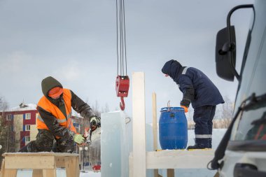 İşçi koruyucu bir kask içinde tesisatçısı ve yansıtıcı yelek bir buz levha testere ile kesme