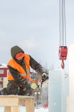 İşçi koruyucu bir kask içinde tesisatçısı ve yansıtıcı yelek bir buz levha testere ile kesme