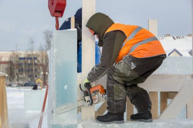 İşçi koruyucu bir kask içinde tesisatçısı ve yansıtıcı yelek bir buz levha testere ile kesme