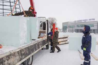Birleştiriciler vinç kullanarak bir arabadan buz panelleri indirir.