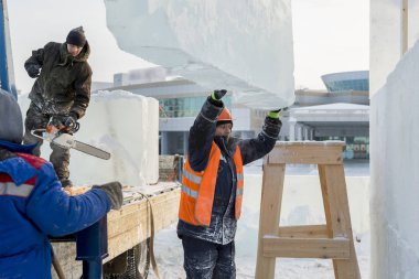 Ceketli ve kasklı bir askıcı buz kalıplarını boşaltıyor.