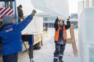 Ceketli ve kasklı bir askıcı buz kalıplarını boşaltıyor.
