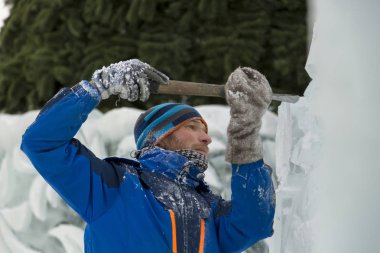 Heykeltıraş, Noel için bir buz kalıbını keskiyle kesiyor.