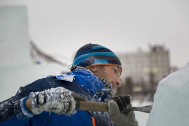 Heykeltıraş, Noel için bir buz kalıbını keskiyle kesiyor.