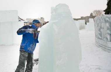 Heykeltıraş, Noel için bir buz kalıbını keskiyle kesiyor.