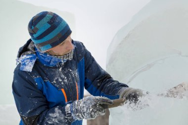 Heykeltıraş, Noel için bir buz kalıbını keskiyle kesiyor.