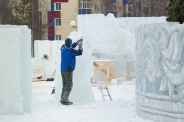 Heykeltıraş, Noel için bir buz kalıbını keskiyle kesiyor.