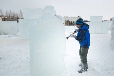 Heykeltıraş, Noel için bir buz kalıbını keskiyle kesiyor.