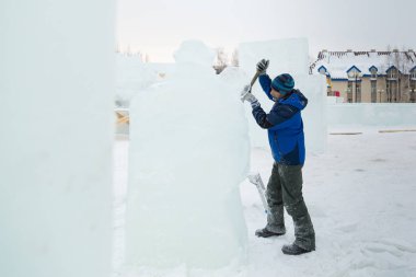 Heykeltıraş, Noel için bir buz kalıbını keskiyle kesiyor.