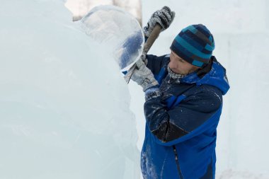 Heykeltıraş, Noel için bir buz kalıbını keskiyle kesiyor.