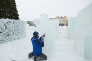 Heykeltıraş, Noel için bir buz kalıbını keskiyle kesiyor.