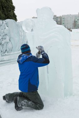 Heykeltıraş, Noel için bir buz kalıbını keskiyle kesiyor.