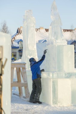 Sanatçı, buzun üzerinde geleceğin buz figürünün hatlarını çizer.