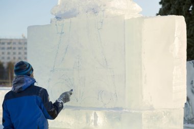 Sanatçı, buzun üzerinde geleceğin buz figürünün hatlarını çizer.