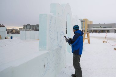 Sanatçı, buzun üzerinde geleceğin buz figürünün hatlarını çizer.