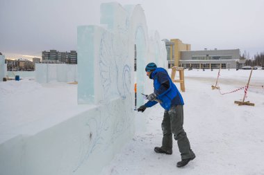 Sanatçı, buzun üzerinde geleceğin buz figürünün hatlarını çizer.