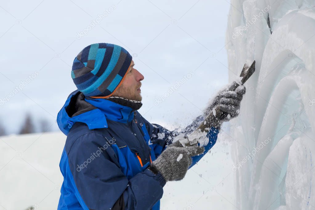 The sculptor cuts an ice figure for Christmas from a block of ice with a chisel