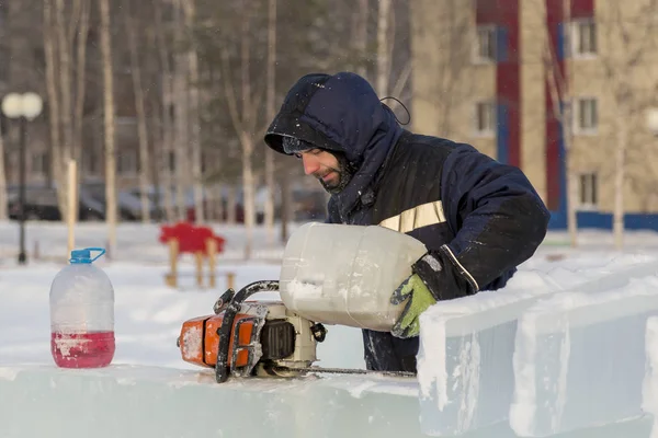 İşçi el ile Gönderen benzinli testere doldurur
