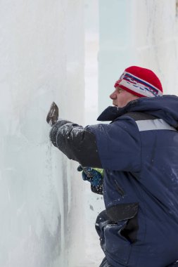 Heykeltıraş, Noel için bir buz kalıbını keskiyle kesiyor.
