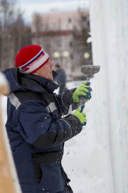 Heykeltıraş, Noel için bir buz kalıbını keskiyle kesiyor.