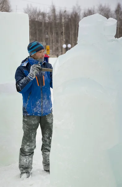 The sculptor cuts an ice figure out of a block of ice for Christmas