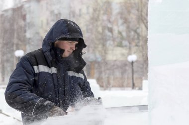 Heykeltıraş, buzdan bir buz figürünü Noel için elektrikli testere ile kesiyor.