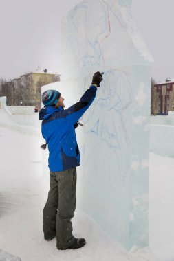Sanatçı, buzun üzerinde geleceğin buz figürünün hatlarını çizer.