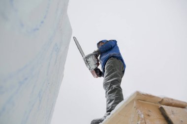 Heykeltıraş, buzdan bir buz figürünü Noel için elektrikli testere ile kesiyor.