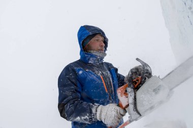 Heykeltıraş, buzdan bir buz figürünü Noel için elektrikli testere ile kesiyor.