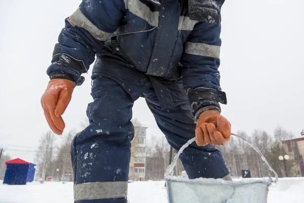 Buz kasabasının toplanma yerinde elinde kova olan bir işçi.