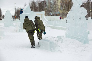 İki işçi forseps ile buz kamp derleme sitenin etrafına bir buz bloğu çekerek