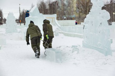 İki işçi forseps ile buz kamp derleme sitenin etrafına bir buz bloğu çekerek