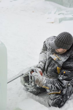İşçi buz şehrin montaj yerinde elinde testere ile