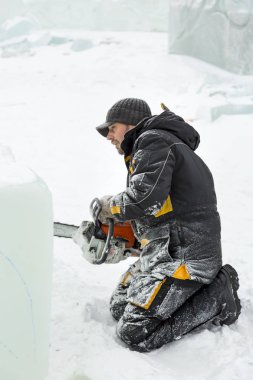 İşçi buz şehrin montaj yerinde elinde testere ile