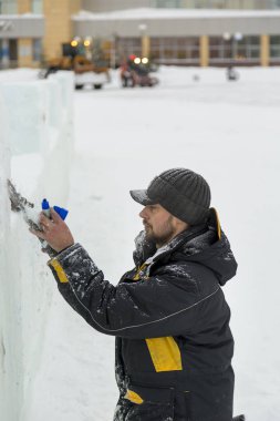Heykeltıraş buz kalıbından bir buz kalıbını kesiyor.