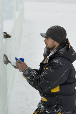 Heykeltıraş buz kalıbından bir buz kalıbını kesiyor.