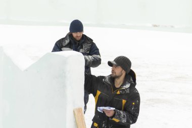 Sanatçı, buzun üzerinde geleceğin buz figürünün hatlarını çizer.