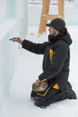 Sanatçı, buzun üzerinde geleceğin buz figürünün hatlarını çizer.
