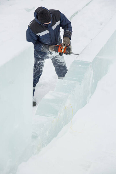Worker with a chainsaw in hand at the ice figure