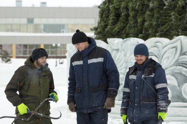 Noel ağacı arka plan üzerinde buz şehrin montaj yerinde üç işçi