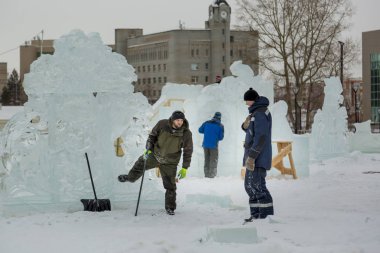 Elinde levyeyle buz kasabasının inşaat alanında çalışan bir işçi.